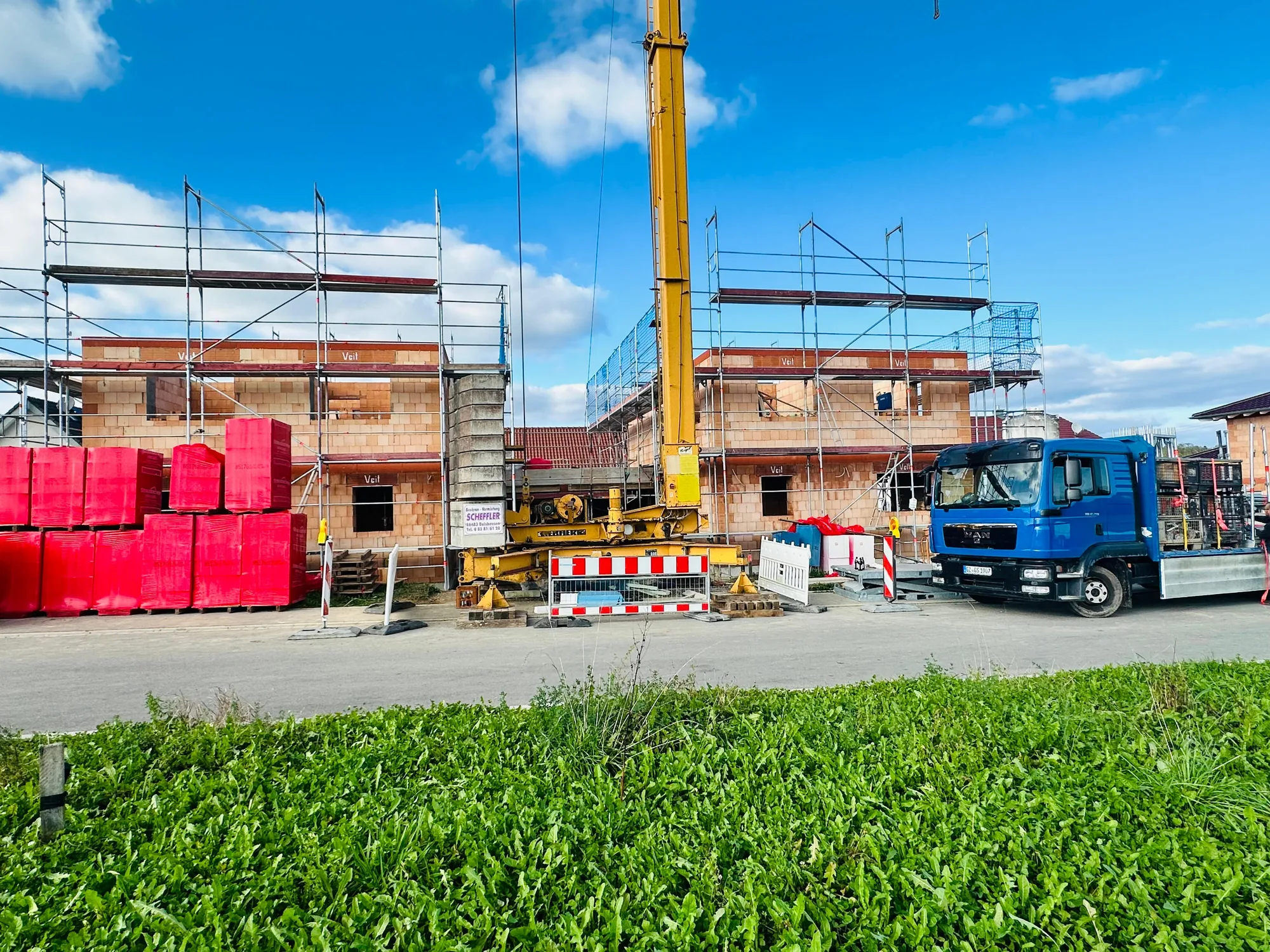 Zwei Neubauten mit Baugerüst und Baustellenfahrzeugen